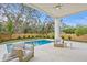 Inviting covered patio overlooking pool and landscaped backyard; features fan and comfortable seating at 2554 Arlington St, Sarasota, FL 34239