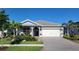 Inviting home featuring a brick driveway, a two-car garage and lush tropical landscaping at 26017 Seastone Dr, Englewood, FL 34223