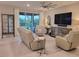 Open-concept living room with comfortable seating, large TV, and sliding glass doors to the outdoor space at 26017 Seastone Dr, Englewood, FL 34223