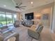 Bright living room features comfortable seating, a mirrored accent cabinet, and sliding doors to the lanai at 26017 Seastone Dr, Englewood, FL 34223