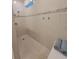 Shower with neutral colored tile, a tiled accent strip, and integrated storage shelves at 26017 Seastone Dr, Englewood, FL 34223