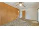 Bedroom featuring a neutral rug, ceiling fan, adjacent to a bathroom, and wood paneled wall at 2702 Bedford Way, Sarasota, FL 34239