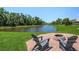Backyard view of a pond and a brick patio with comfortable seating surrounding a firepit at 3015 160Th E Ter, Parrish, FL 34219