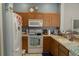 Functional kitchen featuring wood cabinets, white appliances, and neutral countertops at 3784 Parkridge Cir # 22-203, Sarasota, FL 34243