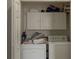 Bright laundry area featuring a washer, dryer, storage cabinets, and cleaning supplies at 3784 Parkridge Cir # 22-203, Sarasota, FL 34243