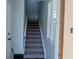 Carpeted staircase leading upstairs with light-blue walls and a window with white blinds at 3784 Parkridge Cir # 22-203, Sarasota, FL 34243