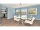 Sunlit dining area featuring a modern glass-top table, white chairs, and views into the adjacent kitchen at 4512 26Th S Ave, Tampa, FL 33619