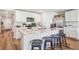 Modern kitchen with white cabinetry, marble countertops, a breakfast bar with stools, and hardwood floors at 4513 Dusky Dawn Ln, Palmetto, FL 34221