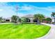 Beautiful clubhouse with a manicured lawn, palm trees, and an American flag at 5217 Chase Oaks Dr, Sarasota, FL 34241