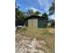 Green storage shed with double doors in the backyard, offering practical storage solutions at 6013 Idle A While Cir, Dade City, FL 33523