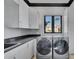 Modern laundry room with gray countertop, white cabinets, and newer washer/dryer at 641 Ranger Ln, Longboat Key, FL 34228