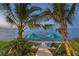 Beautiful waterfront view showcasing lounge chairs and turquoise umbrellas between swaying palm trees at 641 Ranger Ln, Longboat Key, FL 34228