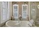 Close up of a soaking tub area with elegant arched windows, plantation shutters, and stylish décor at 6919 Dominion Ln, Lakewood Ranch, FL 34202