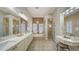 Bright bathroom featuring double sinks, a soaking tub under arched windows, and a glass enclosed shower at 6919 Dominion Ln, Lakewood Ranch, FL 34202