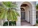Stunning arched entryway and decorative double doors framed by lush landscaping and a mature palm tree at 6919 Dominion Ln, Lakewood Ranch, FL 34202