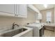 Organized laundry room with white cabinets, marble counters, a sink, and modern machines at 6919 Dominion Ln, Lakewood Ranch, FL 34202