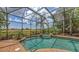An in-ground pool with a screen enclosure and lush landscaping beyond the pool area at 6919 Dominion Ln, Lakewood Ranch, FL 34202