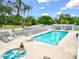 Relaxing pool area with a hot tub, lounge chairs, white fencing, and manicured landscaping for a luxurious community feel at 7039 Strand Cir # 34-201, Bradenton, FL 34203