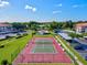 Aerial view of a meticulously maintained tennis court adjacent to a community pool, cabana, parking, and lush green spaces at 7039 Strand Cir # 34-201, Bradenton, FL 34203