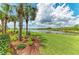 Lush green lawn extends to a picturesque pond, accented by palm trees and bright landscaping at 7315 River Hammock Dr # 101, Bradenton, FL 34212