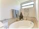 Serene bathroom with a soaking tub, tile surround, decorative accents, and a bright window at 7315 River Hammock Dr # 101, Bradenton, FL 34212