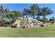 Striking 'River Strand' monument with cascading waterfall set against a backdrop of mature palm trees and manicured lawn at 7315 River Hammock Dr # 101, Bradenton, FL 34212