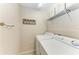 Practical laundry room includes modern washer and dryer with overhead storage shelving and decor at 7315 River Hammock Dr # 101, Bradenton, FL 34212