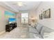 Comfortable living room with a plush gray sofa, TV, ceiling fan, and bright window at 7315 River Hammock Dr # 101, Bradenton, FL 34212