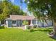 Inviting home featuring lush green lawn, mature trees, and a welcoming red front door at 8304 Fishhawk Ave, New Port Richey, FL 34653