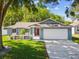 Charming single-story home with a well-manicured lawn, colorful landscaping, and a bright red front door at 8304 Fishhawk Ave, New Port Richey, FL 34653