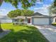 Beautiful single story home with a well-maintained lawn, a red door, and an attached two-car garage at 8304 Fishhawk Ave, New Port Richey, FL 34653