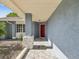 Inviting front porch with stone accents, a red door, and a covered entry providing shade and style at 8304 Fishhawk Ave, New Port Richey, FL 34653