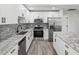 Modern kitchen featuring white cabinets, stainless steel appliances, granite countertops, and a stylish backsplash at 8304 Fishhawk Ave, New Port Richey, FL 34653