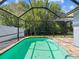 Sparkling in-ground pool enclosed by a screen, surrounded by brick pavers, and backed by lush greenery at 8304 Fishhawk Ave, New Port Richey, FL 34653