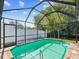 Relax in the screened in-ground pool with a fence in the background and lush green trees at 8304 Fishhawk Ave, New Port Richey, FL 34653
