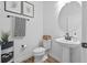 A well-lit half bathroom includes a toilet, sink, mirror, and decorative wall art at 11430 Gallatin Trl, Parrish, FL 34219