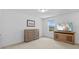 A well-lit bedroom with carpet flooring, light walls, TV, and dresser at 11430 Gallatin Trl, Parrish, FL 34219