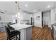 Open concept kitchen with stainless steel appliances, stone counters, bar seating, hardwood floors, and views into the living room at 11430 Gallatin Trl, Parrish, FL 34219