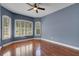 Charming bedroom with a ceiling fan, rich wood flooring, and bright windows with white shutters at 1657 Bonita Bluff Ct, Ruskin, FL 33570