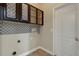 Well-equipped laundry room with patterned backsplash, storage cabinets, and a convenient door at 1657 Bonita Bluff Ct, Ruskin, FL 33570