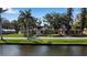 View of the home from across the water, with lawn, mature trees, and a picturesque setting at 1830 Virginia Dr, Bradenton, FL 34205