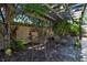 Charming outdoor seating area with a wooden pergola and brick-paved patio surrounded by tropical landscaping at 1830 Virginia Dr, Bradenton, FL 34205