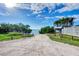 Scenic beach access path with lush greenery, leading to tranquil waters under a bright blue, partially cloudy sky at 1856 Wharf Rd, Sarasota, FL 34231