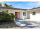 Home featuring a vibrant red front door, neatly trimmed bushes, and a well-kept lawn at 1856 Wharf Rd, Sarasota, FL 34231