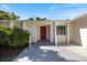 Close-up of the front entrance, featuring a bright red door, decorative gravel, and lush green bushes at 1856 Wharf Rd, Sarasota, FL 34231