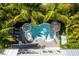 An aerial view of the backyard featuring a uniquely shaped pool, spa, tiki umbrella, and lush landscaping at 212 72Nd, Holmes Beach, FL 34217
