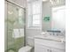 Bathroom with white cabinets, marble counters, large mirror, and glass enclosed shower with marble tiles at 212 72Nd, Holmes Beach, FL 34217
