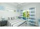 Bright bedroom featuring ceiling fan, balcony access with curtains, and queen bed with stylish striped bedding at 212 72Nd, Holmes Beach, FL 34217