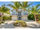 An attractive two-story home with palm trees and a ground-level entrance leading to a garage at 212 72Nd, Holmes Beach, FL 34217