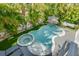 The backyard features a uniquely shaped pool, a spa, lush landscaping, and a hammock for relaxation at 212 72Nd, Holmes Beach, FL 34217